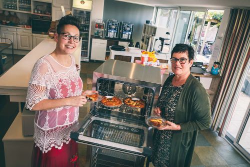 Twee vrouwewlijke collega's bij de oven. 