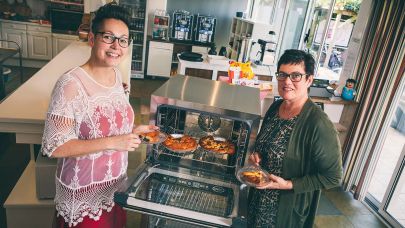 Twee vrouwewlijke collega's bij de oven. 